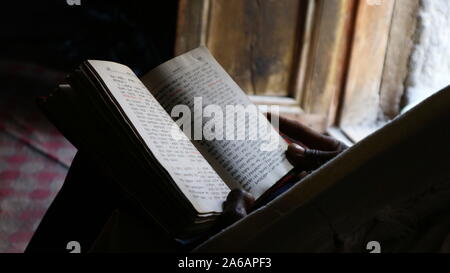 Orthodoxen Mönch äthiopischen Bibel von Tür Licht in Asheton Maryam Kloster mit äthiopischen Schreiben in Soft Focus Stockfoto