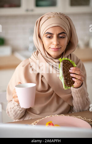 Hübsches Mädchen ihre freie Zeit genießen, während Essen Sandwich und Tee trinken. Stockfoto