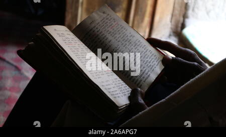 Orthodoxen Mönch äthiopischen Bibel von Tür Licht in Asheton Maryam Kloster mit äthiopischen Schreiben in Soft Focus Stockfoto