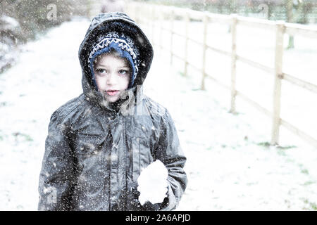 Einen kleinen Jungen mit ADHS, Autismus, Asperger-syndrom spielen in den schweren Schnee fallen, Schneebälle, zu Weihnachten, Weihnachten, Weihnachten schneit Stockfoto