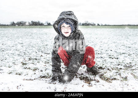 Einen kleinen Jungen mit ADHS, Autismus, Asperger-syndrom spielen in den schweren Schnee fallen, Schneebälle, zu Weihnachten, Weihnachten, Weihnachten schneit Stockfoto