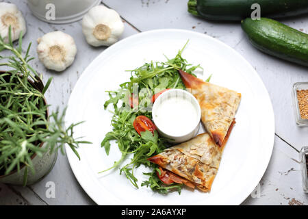 Vegetarisches Essen. Knödel aus Blätterteig, gefüllt mit Gemüse und Pilzen, serviert mit Knoblauch Sauce und grünem Salat Stockfoto