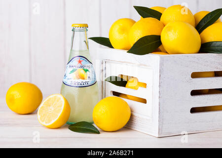 LONDON, Großbritannien - 27 April, 2018: Glas Flasche San Pellegrino sparkling Lemon Soda Drink auf Holz- Hintergrund mit frischen Zitronen in das weiße Feld. Stockfoto