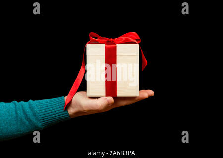 Ein Mann hält ein Weihnachtsgeschenk auf schwarzem Hintergrund Stockfoto