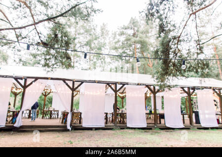 Verschwommenes Foto von hölzernen Hütte Restaurant mit Holztischen und -stühlen., mit Glühbirnen Vintage Design des Restaurants in den Wald in eingerichtet Stockfoto