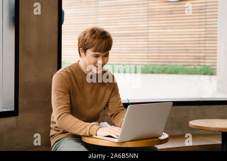 Männliche freelancer Verbindung über Laptop, nachdenklich Geschäftsmann Arbeiten am Notebook Wireless, während an den hölzernen Tisch sitzen in modernen Kaffee sho Stockfoto