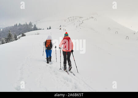 Zwei Frauen, die Freunde wandern und Skitouren nebeneinander auf einem Bergrücken, mit bedecktem Himmel, oben Azuga Ski Resort, Prahova Valley, Baiului Gebirge, Romani Stockfoto