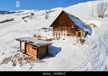 Holzhütte und Baracken auf einer Gefällstrecke Les Sybelles Skigebiet, Frankreich, an einem sonnigen Tag mit blauen Himmel, dem frühen Frühling. Stockfoto