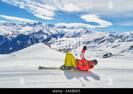 Frau auf Skiern Les Sybelles Skigebiet posieren, auf einem blauen Himmel sonniger Tag, mit Aguilles d Arves Peak im Rücken, zusammen mit anderen Gipfeln. Stockfoto