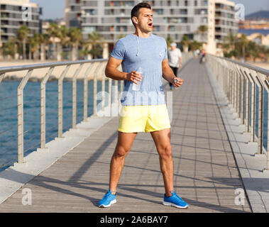 Portrait von Gesund fit Mann Ausruhen nach outdoor Training, mit einer Flasche Wasser Stockfoto