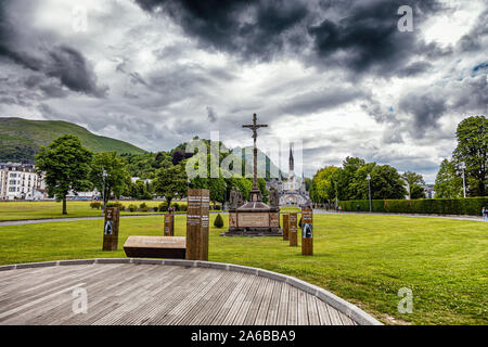 LOURDES - JUNI - 15 - 2019: christliche Kreuz auf einem Hintergrund der Basilika Unserer Lieben Frau vom Rosenkranz in Lourdes, Frankreich Stockfoto