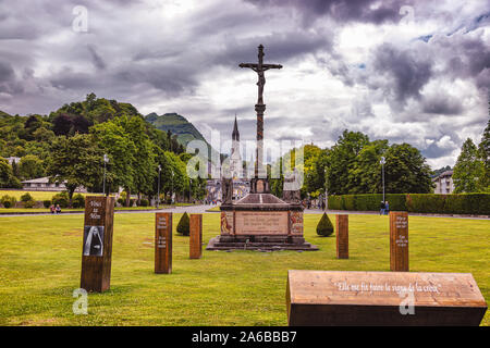 LOURDES - JUNI - 15 - 2019: christliche Kreuz auf einem Hintergrund der Basilika Unserer Lieben Frau vom Rosenkranz in Lourdes, Frankreich Stockfoto