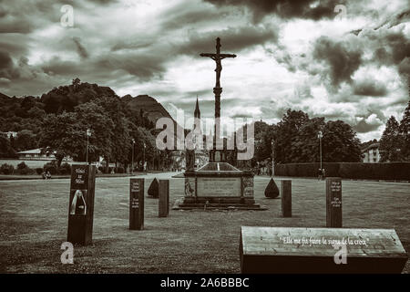 LOURDES - JUNI - 15 - 2019: christliche Kreuz auf einem Hintergrund der Basilika Unserer Lieben Frau vom Rosenkranz in Lourdes, Frankreich Stockfoto