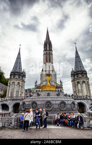 LOURDES - JUNI - 15 - 2019: christliche Kreuz auf einem Hintergrund der Basilika Unserer Lieben Frau vom Rosenkranz in Lourdes, Frankreich Stockfoto