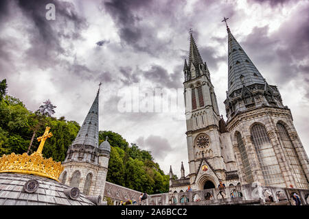 LOURDES - JUNI - 15 - 2019: christliche Kreuz auf einem Hintergrund der Basilika Unserer Lieben Frau vom Rosenkranz in Lourdes, Frankreich Stockfoto