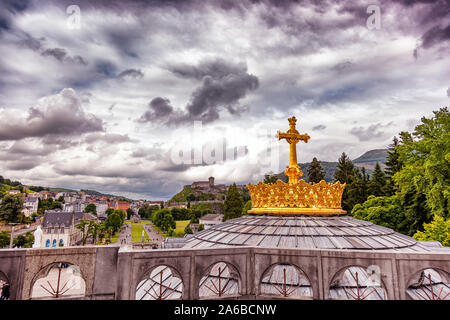 LOURDES - JUNI - 15 - 2019: christliche Kreuz auf einem Hintergrund der Basilika Unserer Lieben Frau vom Rosenkranz in Lourdes, Frankreich Stockfoto