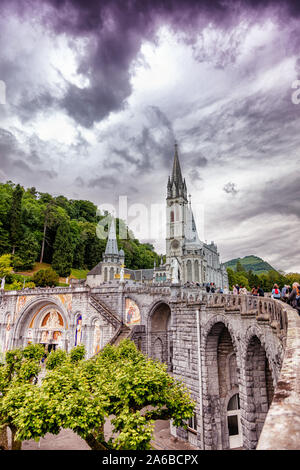 LOURDES - JUNI - 15 - 2019: christliche Kreuz auf einem Hintergrund der Basilika Unserer Lieben Frau vom Rosenkranz in Lourdes, Frankreich Stockfoto