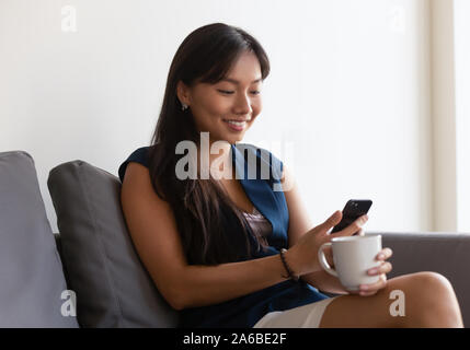 Lächelnd asiatischen Geschäftsfrau mit Phone, Tasse Kaffee Stockfoto