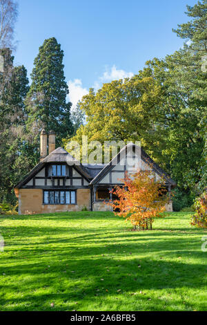 Reetdachhaus und Bäume im Herbst bei Batsford Arboretum, Cotswolds, Moreton-in-Marsh, Gloucestershire, England. Stockfoto