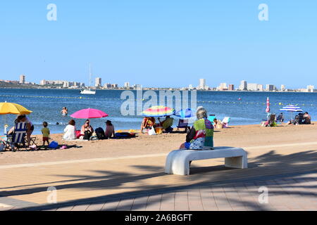 Urlauber am Strand von Mar de Cristal, Mar Menor, Murcia, Spanien sitzen Stockfoto