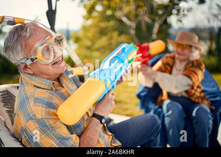 Lächelnd Senior paar Spielen mit Wasser Pistole Stockfoto