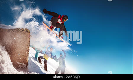 Snowboarder springt von Big Rock gegen Gruppe von Cheerleadern Stockfoto