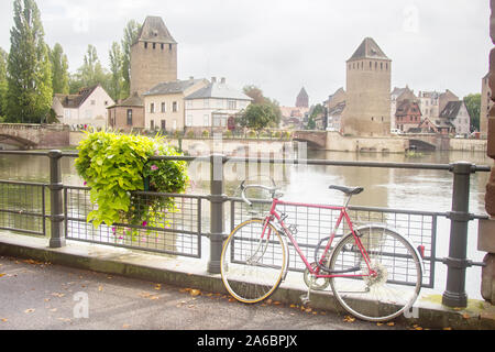 Colmar, Frankreich. Brücke in der Stadt, mit Blick auf den Fluss Lauch und die alten Türme. Blume auf dem Geländer der Brücke und parkte das Bik Stockfoto