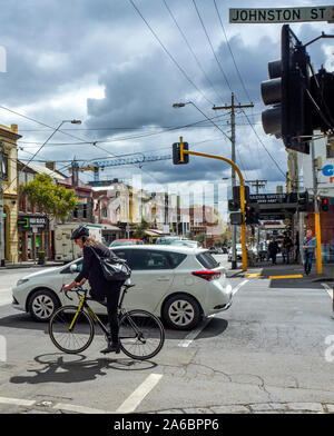 Weibliche Radfahrer reiten ihr Fahrrad entlang Johnston St Kreuzung Smith St Collingwood Melbourne, Victoria, Australien. Stockfoto