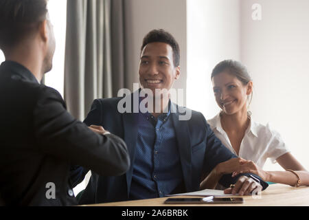 Lächelnd diverse Paar handshaking mit Finanzberater Stockfoto