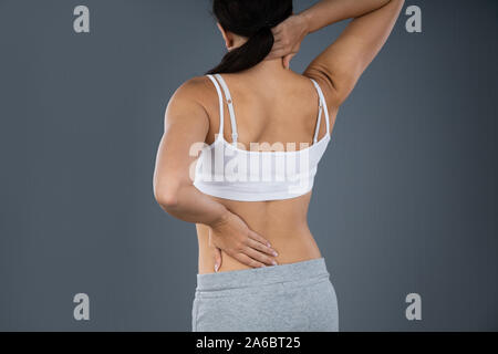 Frau leiden unter Rückenschmerzen Über grauer Hintergrund Stockfoto