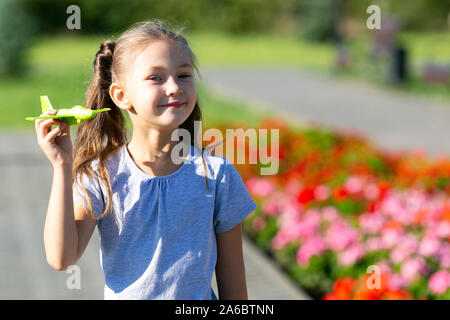 Ein Mädchen hält eine Ebene in die Hand und läuft froh entlang der Straße. Stockfoto