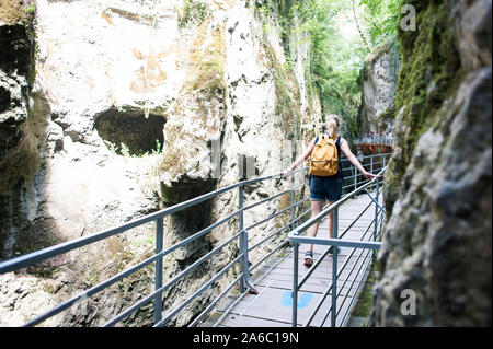 Eine Frau geht auf der Metallbrücke durch die spektakuläre Les Gorges du Fier in Frankreich während des Urlaubs. Stockfoto