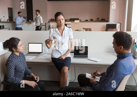 Tausendjährige weibliches Team Leader im Gespräch mit Multirassischen Mannschaftskameraden. Stockfoto