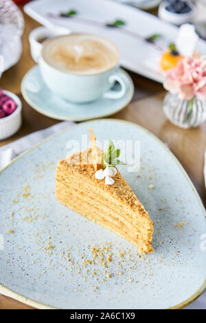 Honig Kuchen mit Baiser und Minze dekoriert.. Frühstück im Café, Kaffee am Morgen. Cappuccino und viele Desserts auf dem Tisch. Stockfoto