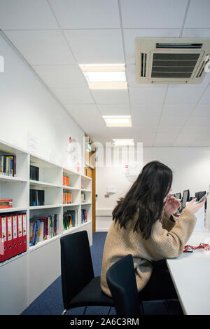 Einer Universität oder einem College Bibliothek mit Büchern in den Regalen, Studenten und Computer Stockfoto