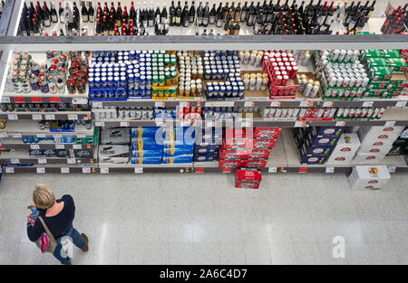 Mit Blick auf die Getränke Gang bei Sainsbury's Supermarkt in Gloucester mit einer Frau, die Auswahl der Biere zu kaufen Stockfoto