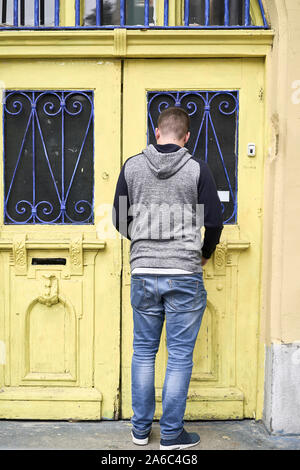 Junger Mann sein Haus betreten. Gelbe Holztür Stockfoto