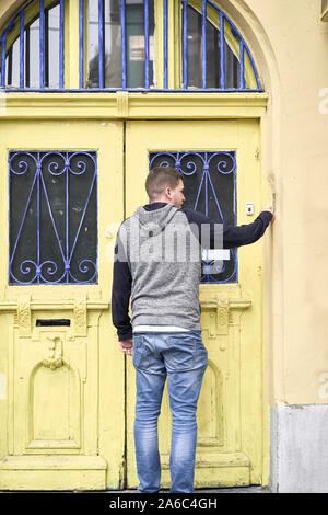 Junger Mann sein Haus betreten. Gelbe Holztür Stockfoto