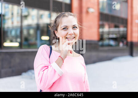 Junge kaukasier Frau Nachdenklich legte die Finger an ihr Kinn auf die moderne Straße im Sommer. Stockfoto