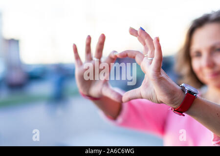 Froh, dass junge stilvolle Kaukasischen brünette Frau in rosa Bluse Schauen durch imaginäre Fernglas auf Sommer Straße. Stockfoto