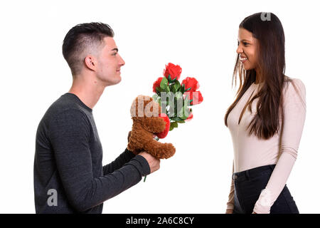 Junge glückliches Paar lächelnd und in der Liebe mit Mann, der rote Rosen Stockfoto