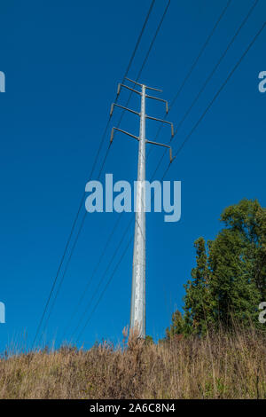 Große power line Tower schneiden durch die Wälder nach oben in den blauen Himmel schauend im Herbst Stockfoto