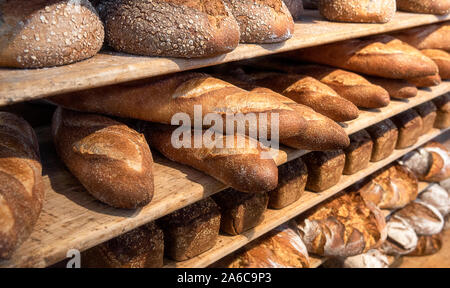Zusammenstellungen von Brot, frisch gebackene auf hölzernen Regalen. Stapel von Brot. Bäckerei Regale voller Brot. Backwaren. Verschiedene Brote und Brötchen. Stockfoto