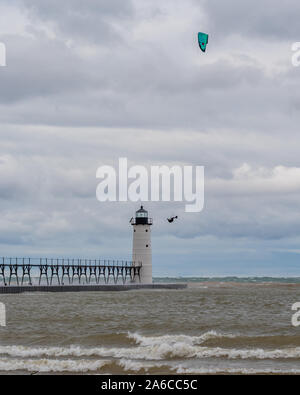 Kitesurfer fliegt hoch vor der Manistee Norden Pierhead Leuchtturm in Michigan, USA. Stockfoto