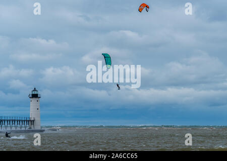 Kitesurfer fliegt hoch vor der Manistee Norden Pierhead Leuchtturm in Michigan, USA, mit einem anderen Kite Surfer ist auf der Fläche der Wasser. Stockfoto