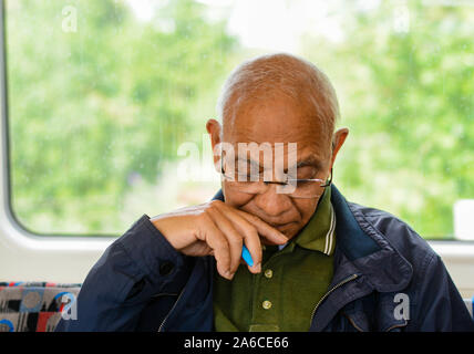 Mittleres Alter Mann in der U-Bahn sehr konzentrieren sich die Lösung einiger Rätsel Spiele aus Zeitung Stockfoto