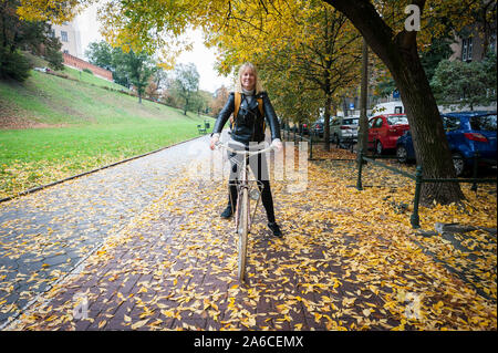 Eine Person, die mit dem Fahrrad auf einem Blatt bedeckt Radweg im Herbst/Herbst Stockfoto