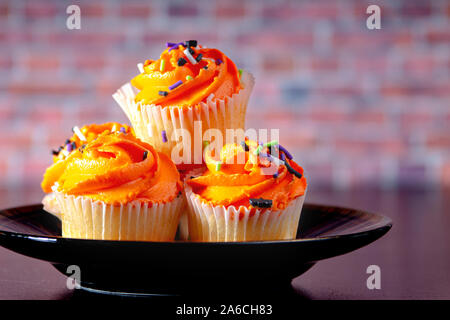 Halloween Muffins auf einer schwarzen Platte mit einem Ziegelstein Hintergrund Stockfoto