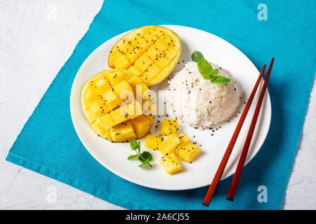 In der Nähe von Thai Dessert, cremige klebrigen Reis mit Kokosmilch gekocht und serviert mit frischen Mango auf einer weißen Platte mit Stäbchen, horizontale Ansicht fr Stockfoto