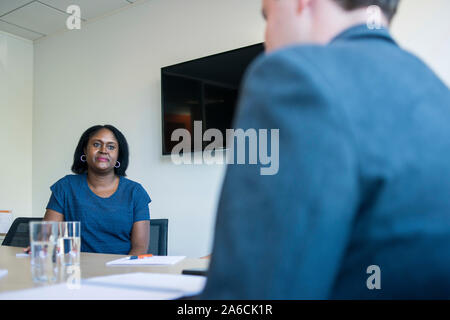 Eine schwarze Frau sitzt an einem Tisch in einer Chancengleichheit Business Stockfoto